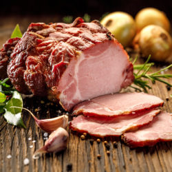 Sliced smoked gammon on a wooden  table with addition of fresh
